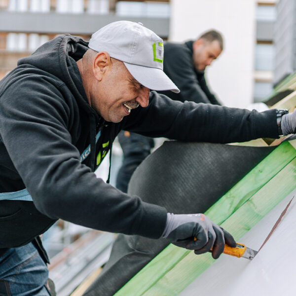 couvreurs de profil qui souris en travaillant sur une toiture de bâtiment public