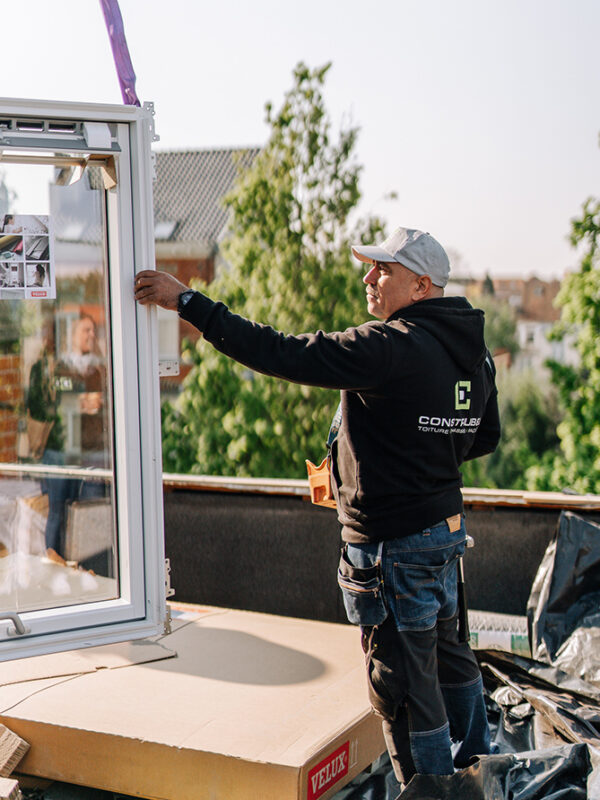 ouvrier Construbel tenant une fenêtre de toit au soleil