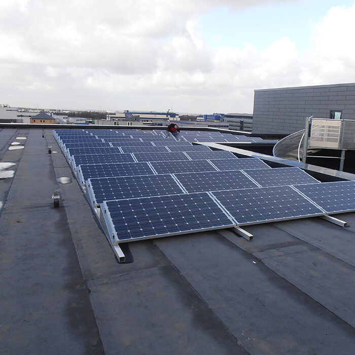 plusieurs rangées de panneaux photovoltaïques sur toit plat d'un bâtiment industriel dans un zoning