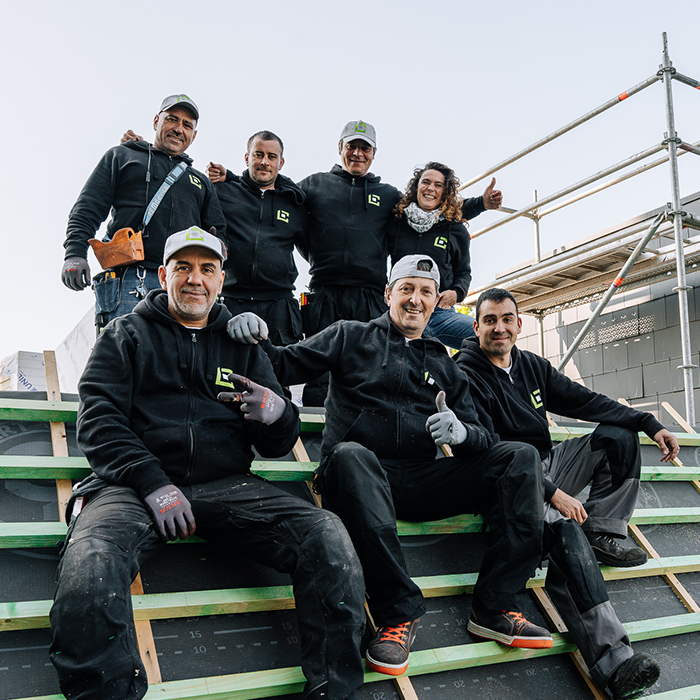 Equipe de 7 ouvriers qui posent pour la photo sur un toit de bâtiment public en chantier